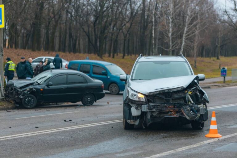 A woman talking on her phone while crouching next to her damaged car.