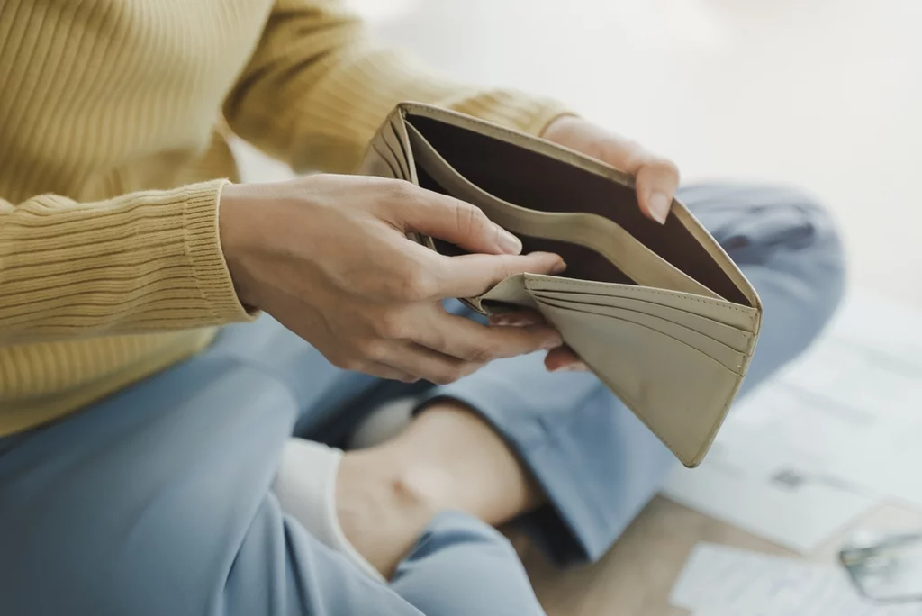 The stressed person sitting on the floor opening empty wallet
