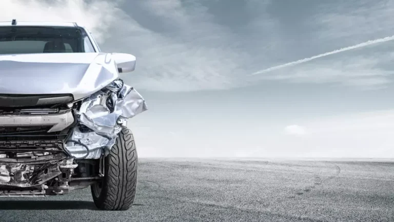 Closeup of the front side of a crashed car on a road.